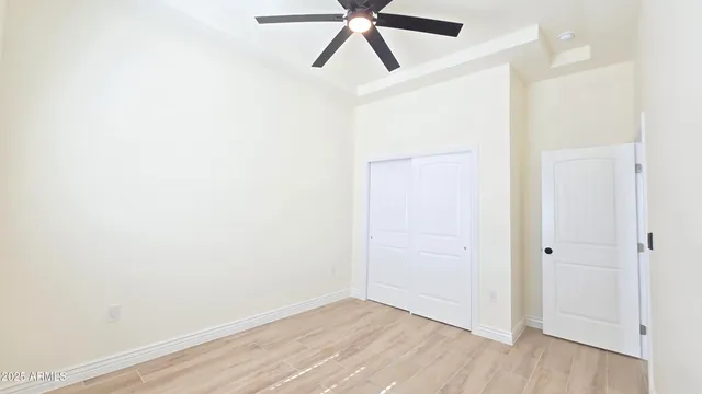 an empty room with wooden floor and ceiling fan
