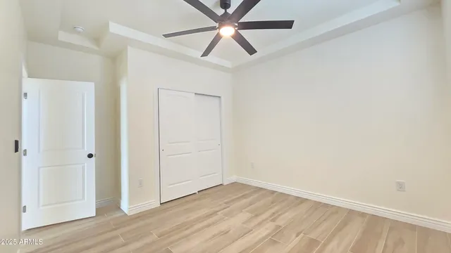 an empty room with wooden floor closet and ceiling fan