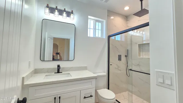 a bathroom with a toilet sink vanity granite and mirror