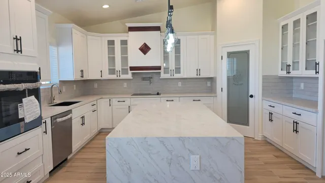 a large kitchen with granite countertop a sink a stove a oven a counter space and cabinets