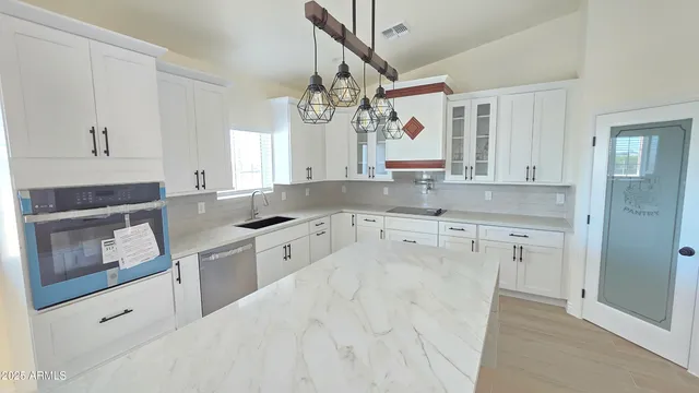 a kitchen with granite countertop a sink cabinets stainless steel appliances and a window