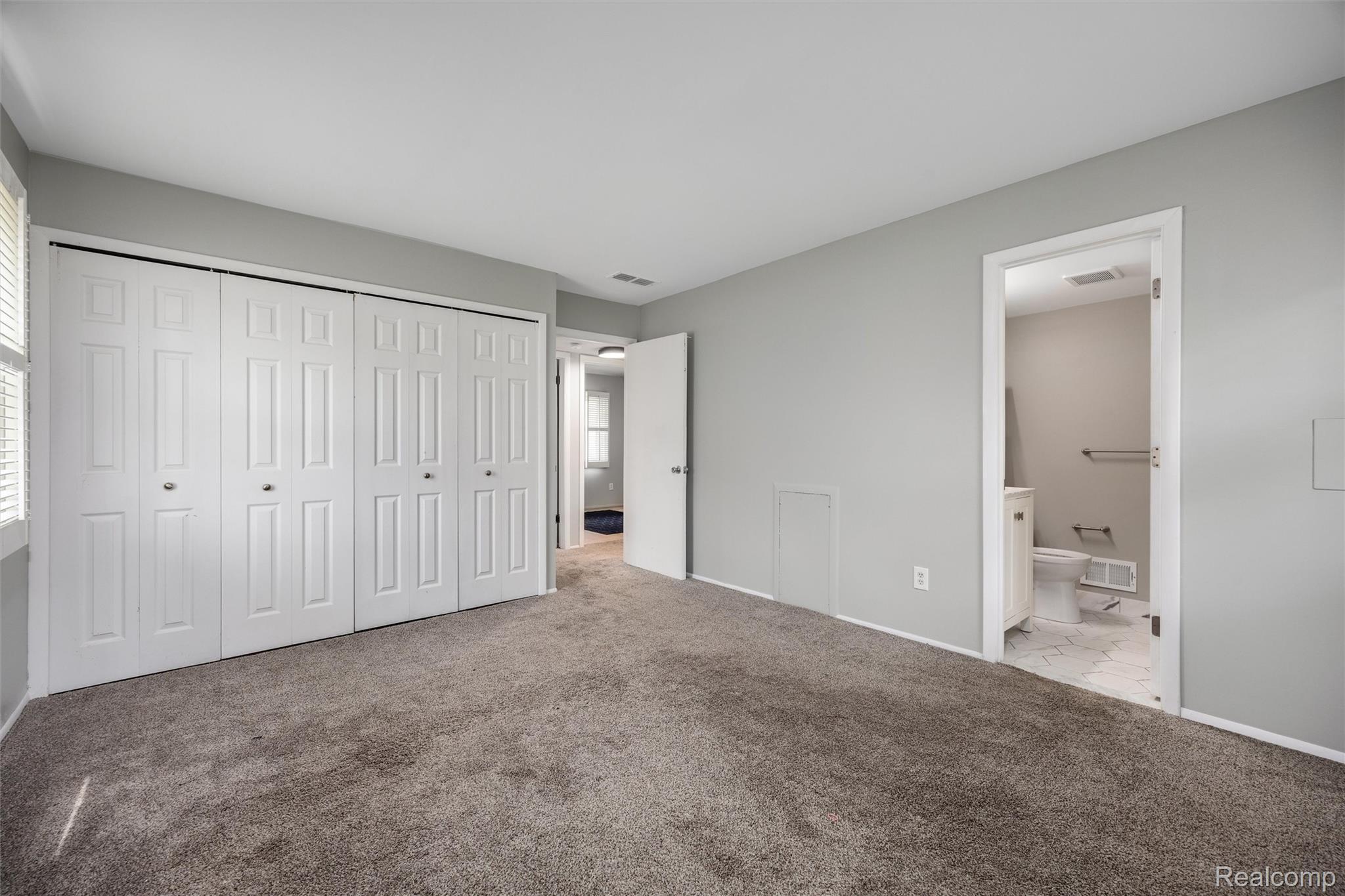 4942 Butler Drive Troy, MI 48085 - Photo 14 of 33 Spacious room featuring neutral gray wall paint, plush carpeting, bi-fold closet doors, and access to a full bathroom with a vanity and toilet