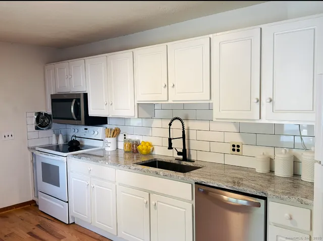 a kitchen with white cabinets and sink