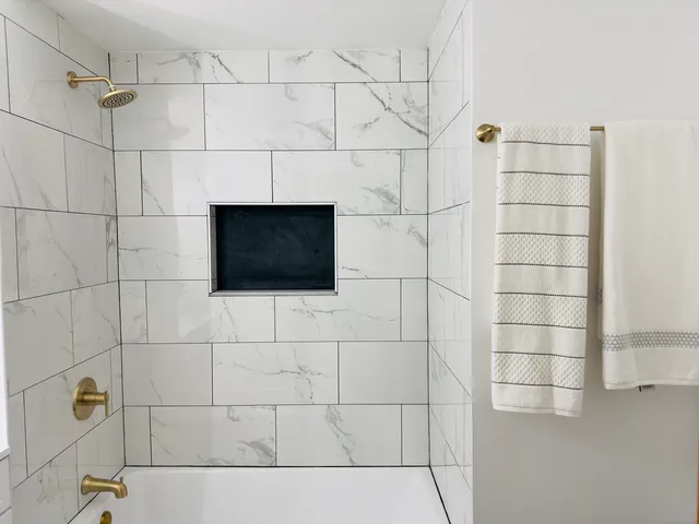 a bathroom with a shower and a tiled wall