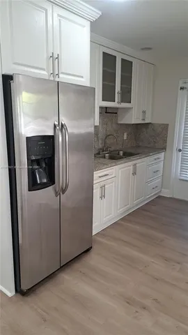 a kitchen with stainless steel appliances granite countertop a refrigerator a stove and a sink with wooden floor