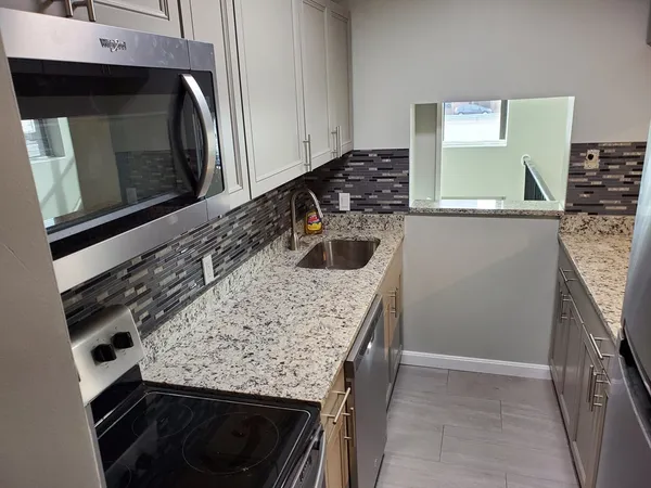 a kitchen with granite countertop a sink and a stove