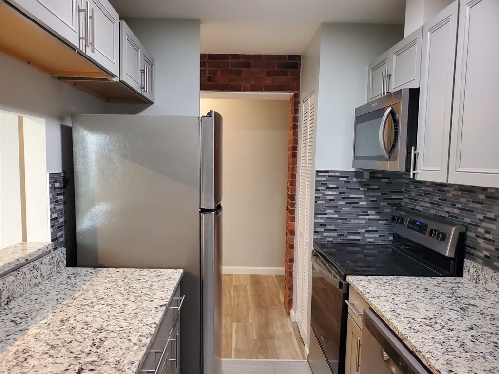 33 Brainerd Road, Unit 112 Boston, MA 02134 - Photo 2 of 23 a kitchen with stainless steel appliances granite countertop a refrigerator and a stove