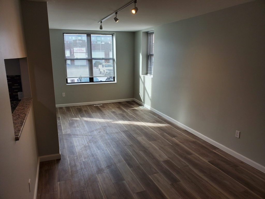 33 Brainerd Road, Unit 112 Boston, MA 02134 - Photo 4 of 23 an empty room with wooden floor and windows