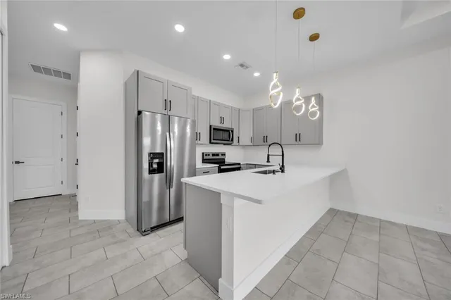 a large white kitchen with a sink and refrigerator