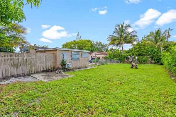 a backyard of a house with table and chairs plants and large tree