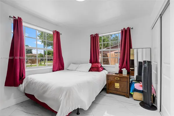 a bedroom with a bed flat screen tv and a large window
