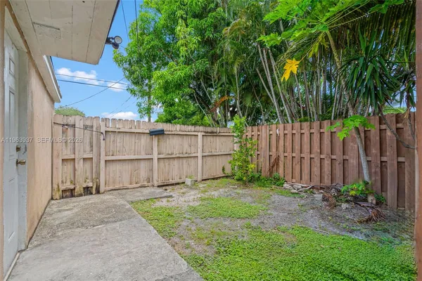 a view of a backyard with large trees and wooden fence