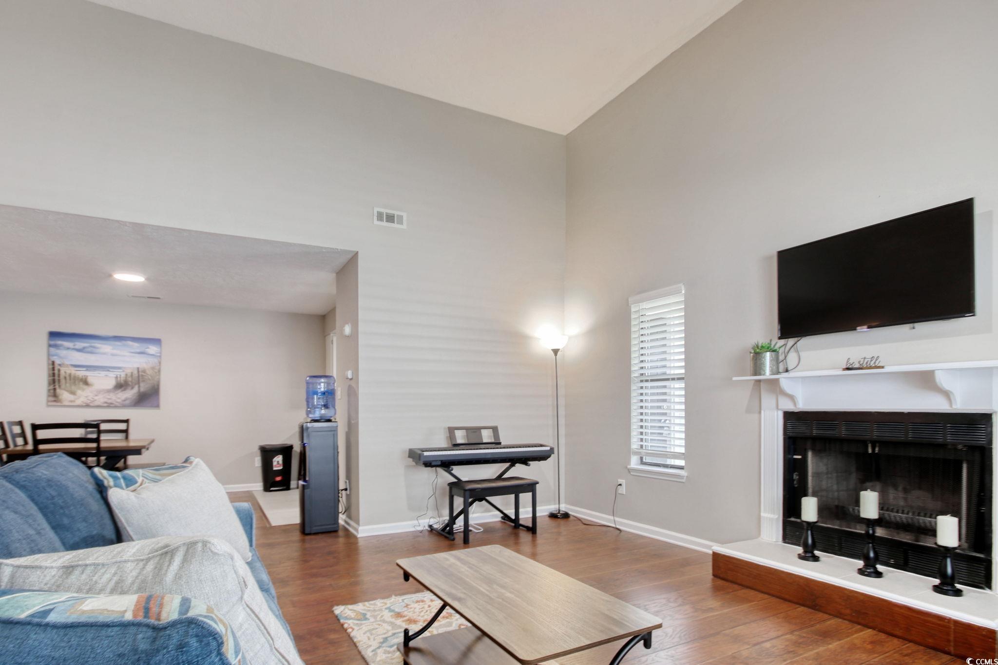 3931 Pinebrook Circle Little River, SC 29566 - Photo 13 of 32 Living room featuring wood flooring, a fireplace with raised hearth, and vaulted ceiling.