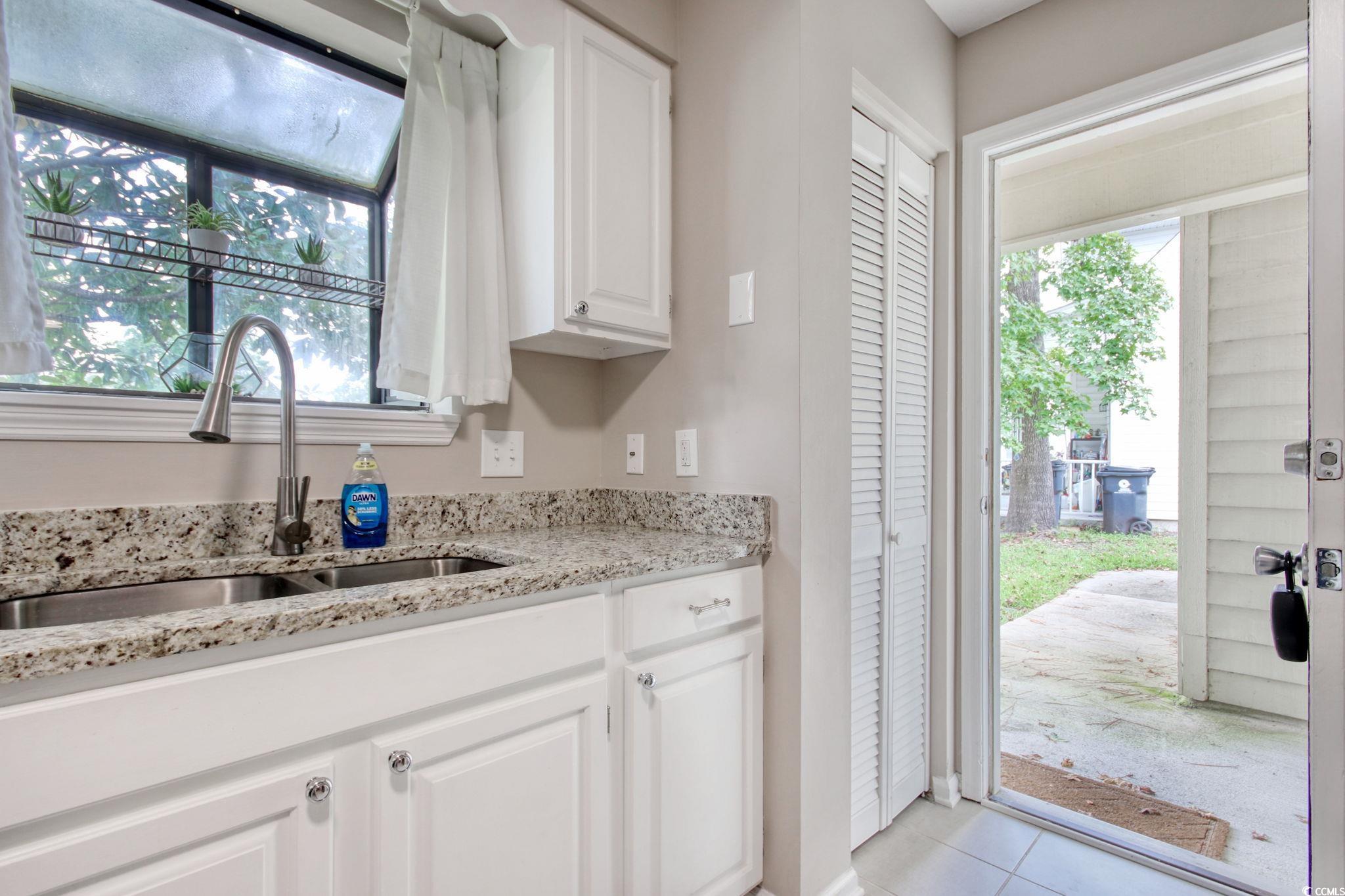 3931 Pinebrook Circle Little River, SC 29566 - Photo 6 of 32 Kitchen at front entry door featuring light stone counters, white cabinetry, and light tile floors
