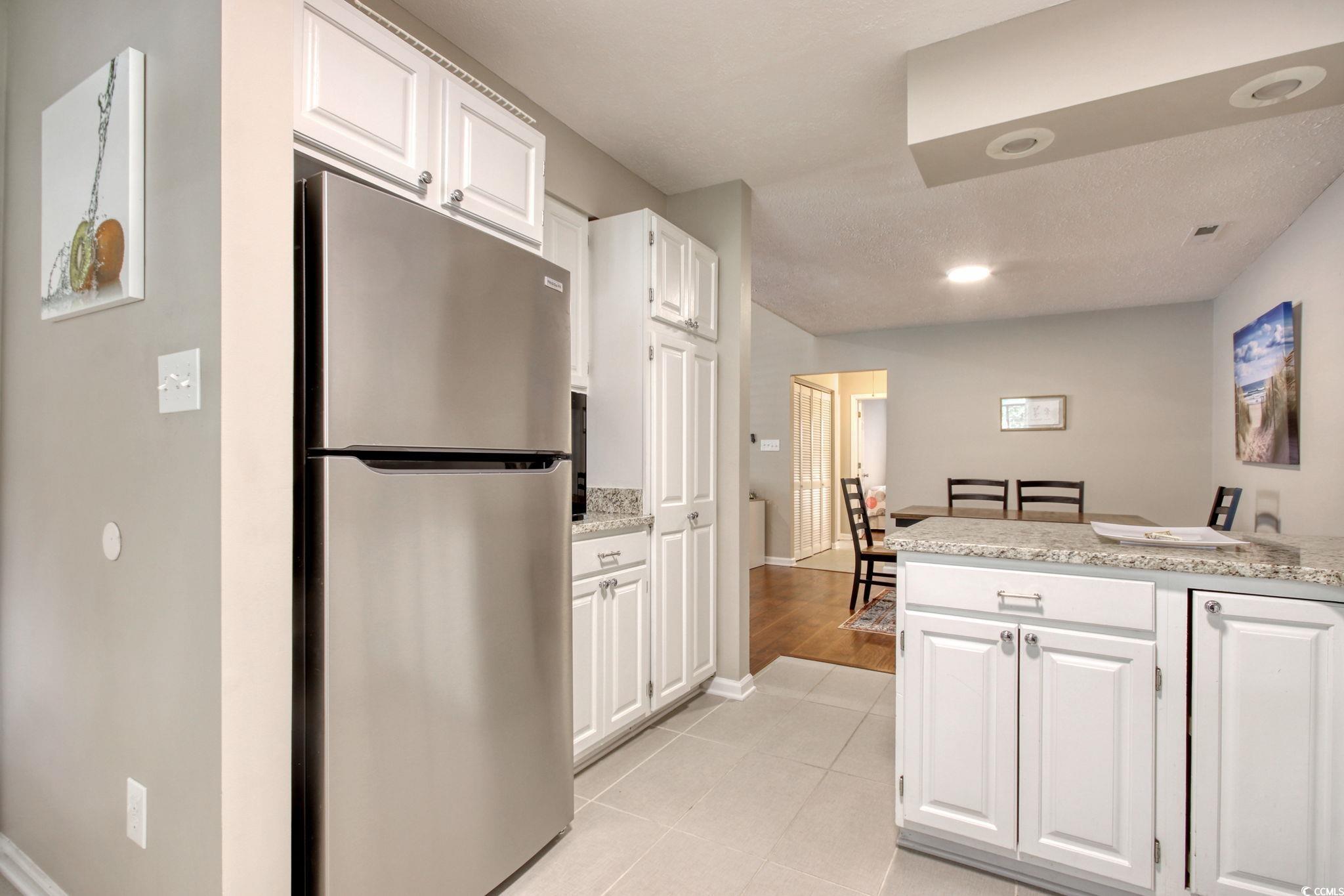 3931 Pinebrook Circle Little River, SC 29566 - Photo 7 of 32 Kitchen featuring all stainless steel appliances, white cabinetry, light tile floors and stone counters.