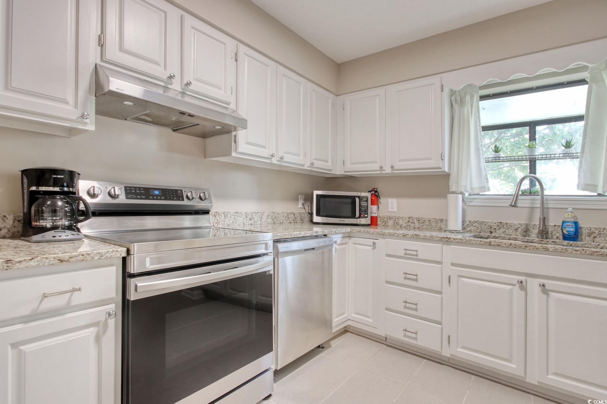 3931 Pinebrook Circle Little River, SC 29566 - Photo 8 of 32 Kitchen featuring stainless steel appliances, white cabinetry, solid surface countertops and light tile flooring.