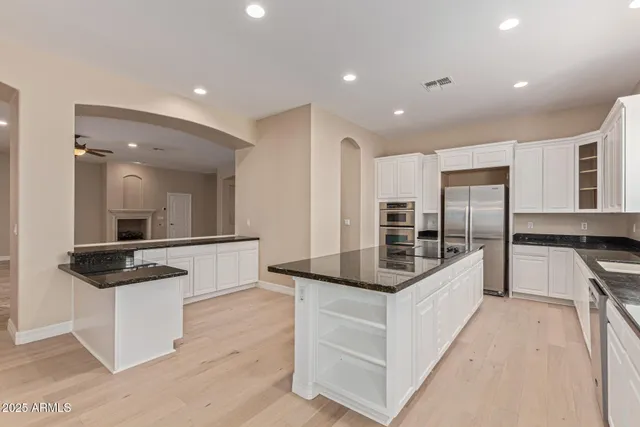 a large white kitchen with kitchen island a sink white cabinets and a granite counter tops