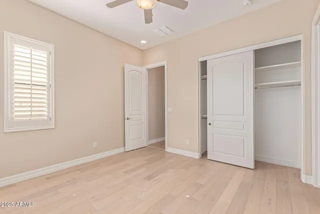 an empty room with wooden floor closet and windows