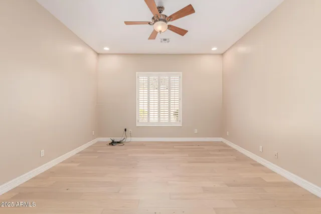 a view of empty room with wooden floor and fan
