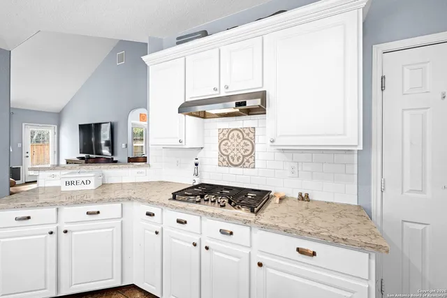 a kitchen with granite countertop a sink and a white wooden cabinets