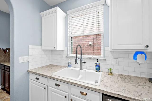 a kitchen with stainless steel appliances kitchen island granite countertop a sink dishwasher a stove a refrigerator with white cabinets and wooden floor