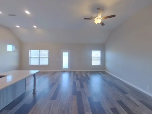 a view of an empty room with a window and wooden floor