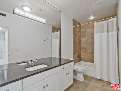 a bathroom with a granite countertop sink a toilet a mirror and shower