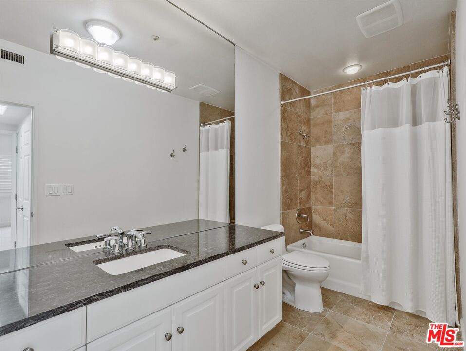 937 12th Street, Unit 308 Santa Monica, CA 90403 - Photo 18 of 39 a bathroom with a granite countertop sink a toilet a mirror and shower
