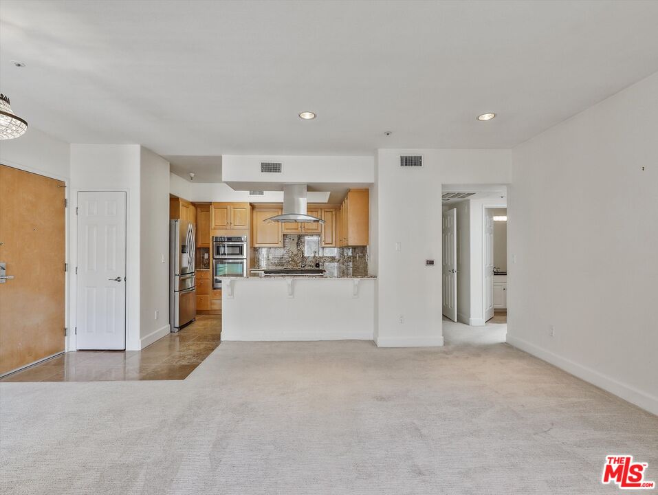 937 12th Street, Unit 308 Santa Monica, CA 90403 - Photo 7 of 39 a view of a kitchen with refrigerator and white cabinets