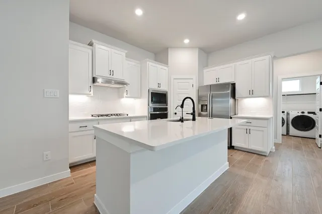 a kitchen with white cabinets and stainless steel appliances