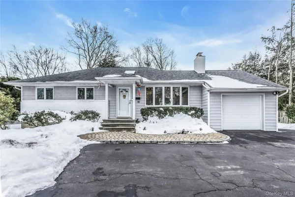 a front view of a house with a dirt yard and a large tree