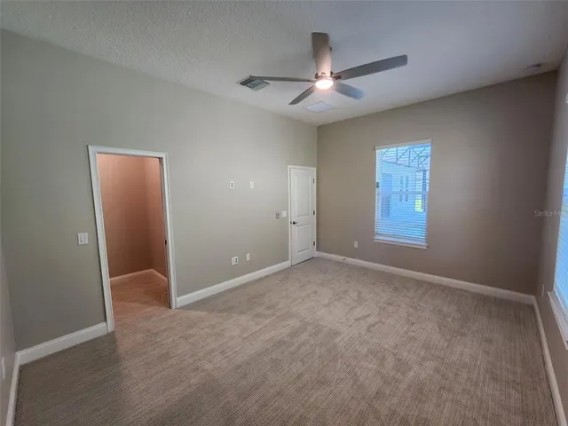 an empty room with windows and fan
