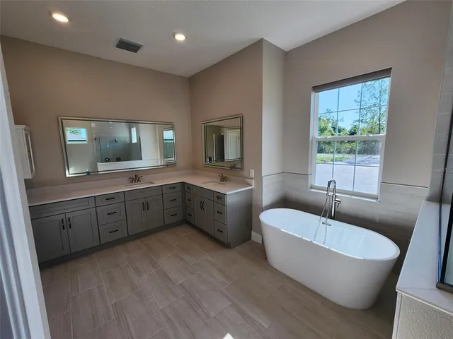 a spacious bathroom with a granite countertop sink mirror and bathtub