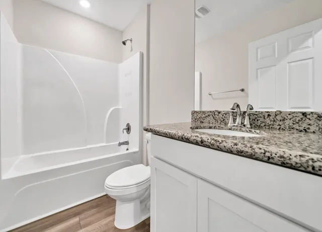 a bathroom with a granite countertop sink toilet and shower
