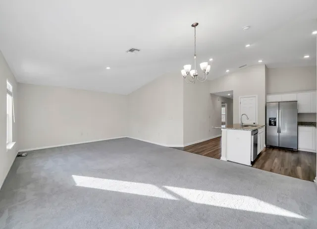 a view of a livingroom with kitchen and chandelier