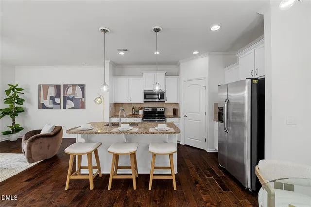 a kitchen with kitchen island a refrigerator and a dining table