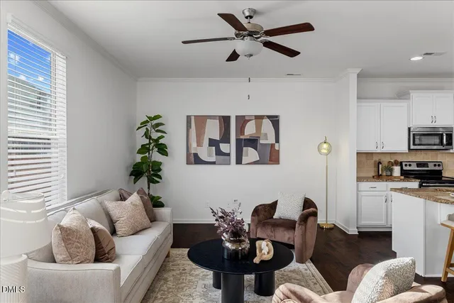 a living room with furniture a chandelier fan and a window