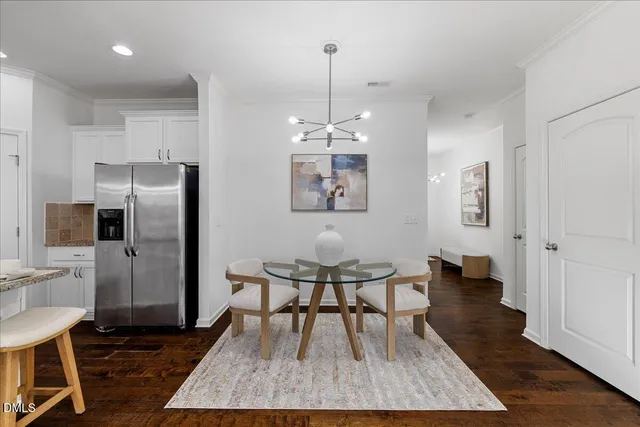 a kitchen with stainless steel appliances granite countertop a dining table chairs refrigerator and sink