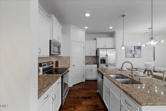 a kitchen with kitchen island granite countertop a sink a counter top space appliances and cabinets