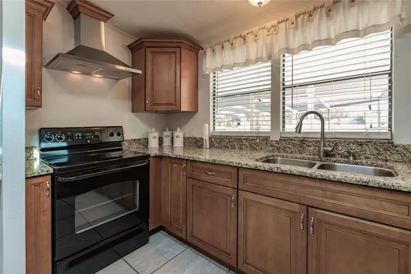 a kitchen with granite countertop a stove a sink and wooden cabinets