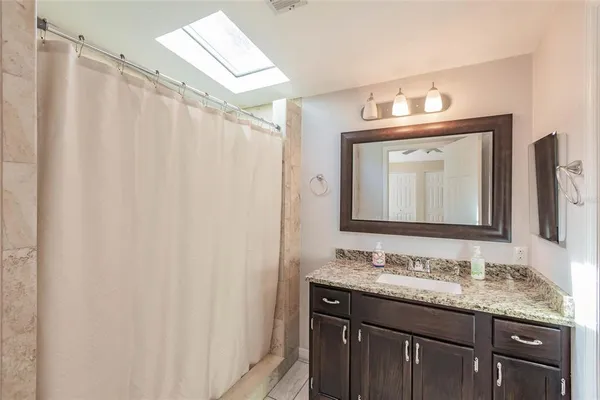 a bathroom with a granite countertop sink a mirror and a shower curtain