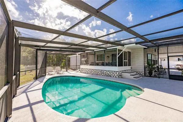 a view of swimming pool with a couches chairs and potted plants