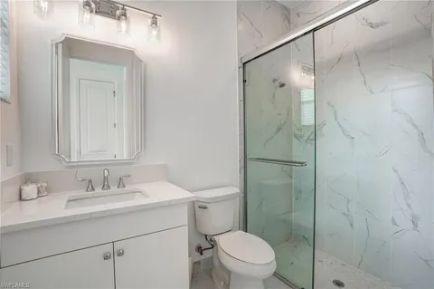 a bathroom with a shower sink vanity mirror and toilet