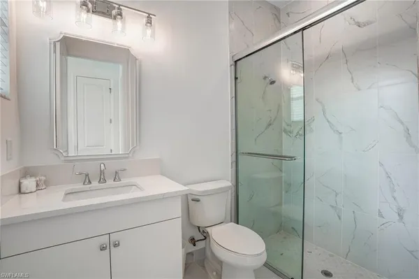 a bathroom with a shower sink vanity mirror and toilet