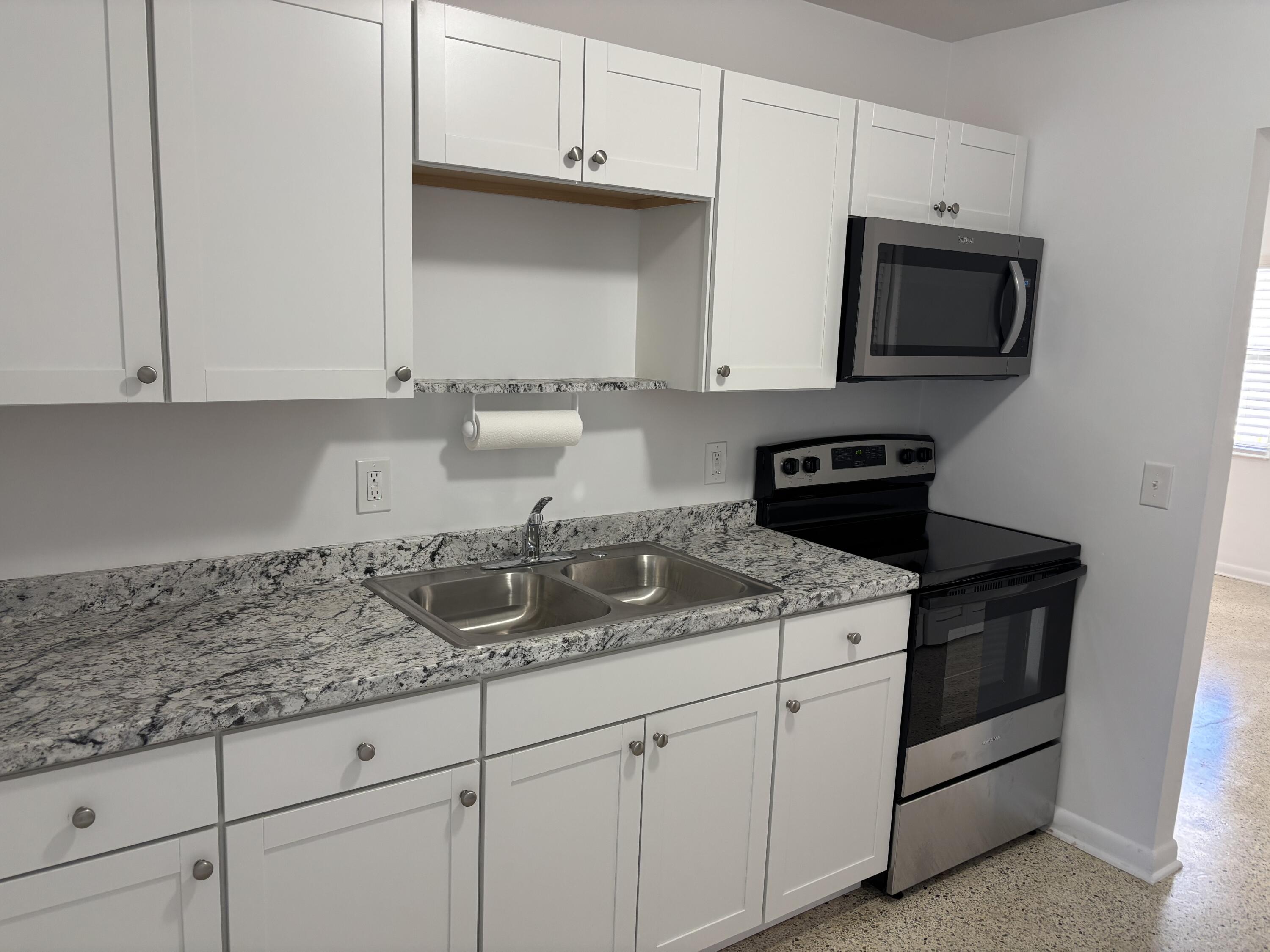 751 Hummingbird Way, Unit 5 North Palm Beach, FL 33408 - Photo 2 of 18 a kitchen with granite countertop white cabinets and a stove