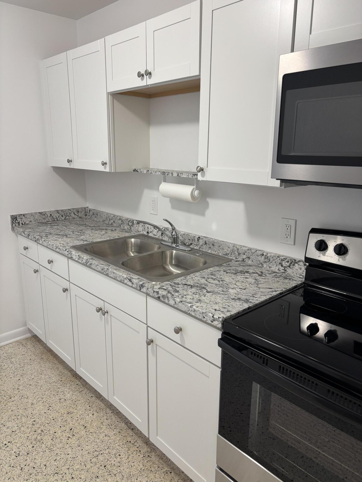 751 Hummingbird Way, Unit 5 North Palm Beach, FL 33408 - Photo 4 of 18 a kitchen with granite countertop white cabinets and a stove