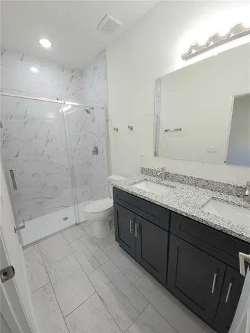 a spacious bathroom with a granite countertop sink a toilet and shower