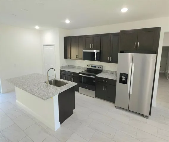 a kitchen with stainless steel appliances granite countertop a sink stove and refrigerator