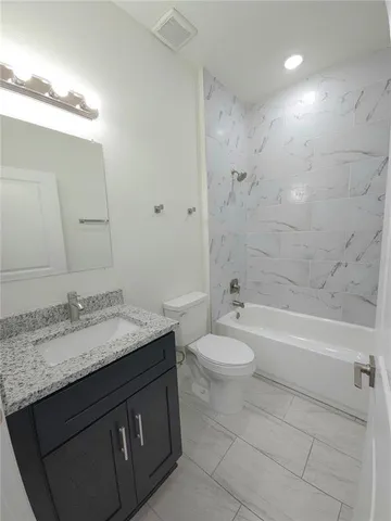 a bathroom with a granite countertop sink toilet mirror and bathtub