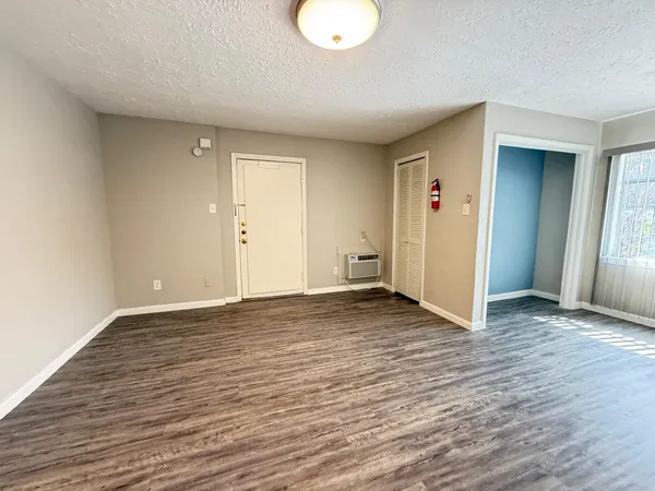 a view of an empty room with wooden floor and closet